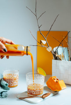 woman serving fresh mango smoothie into a glass