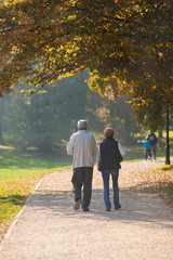 Senior citizen couple taking a walk in a park during autumn morning.