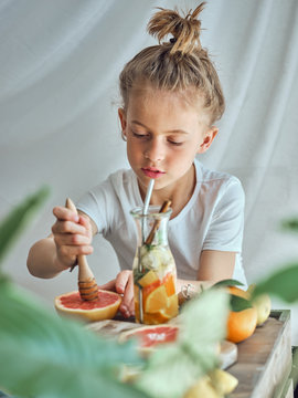 Boy in summer wear with funny hairstyle pressing grapefruit with wooden reamer for juice