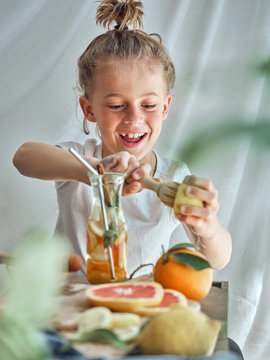 Boy in summer wear with funny hairstyle pressing grapefruit with wooden reamer for juice