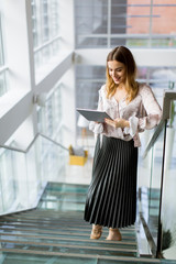 Attractive businesswoman using a digital tablet while standing on the stairs in the office