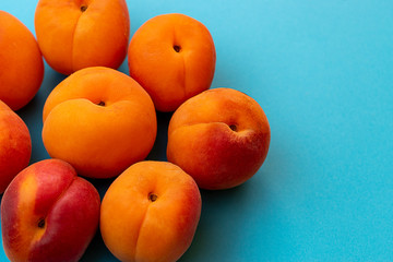 Set of freshly picked apricots, piled on blue background.