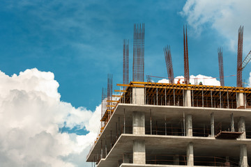 A building under construction with some small workers against sky. Concept: project, building,...