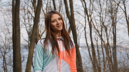 Adorable sporty girl in sportswear smiles in a forest.
