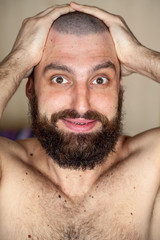 Obraz premium Portrait of man with an unusual hairstyle and beard with a naked torso, looks into the camera 