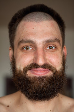 Portrait of man with an unusual hairstyle and beard with a naked torso, looks into the camera 