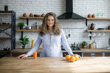 Portrait of a pregnant woman drinking orange juice while watching the house, is in the kitchen.