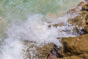 Looking down on waves crashing against rocks, on a beach in Barbados