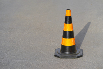 Traffic cone, with black and orange stripes on gray asphalt, copy space. Traffic cone on the road....