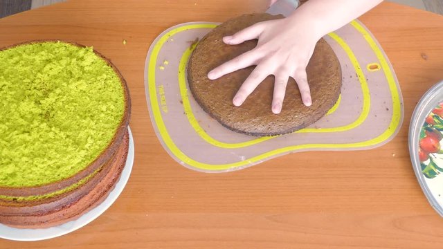 cuts a cake of dark-green color biscuit into two halves