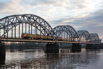 The train travels along the railway bridge across the Daugava river
