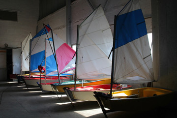 Multicolored sailboats in the boat shed.