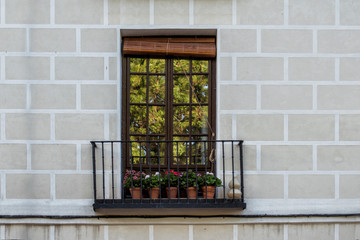 Fototapeta na wymiar antique wooden balcony with flower pots in a facade of a building in Madrid. Spain.