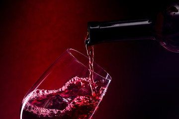 Pouring red wine into the glass over red background