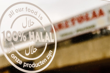 Sign advertising that "al onze producten zijn" ("all our products are) 100% حلالا (Halal) at a Dutch cafe.