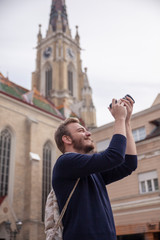 One young man, tourist or traveler using a DSLR camera, in a old European style architecture city behind.