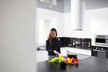 Young woman is preparing healthy food on light kitchen