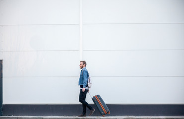 one young man - traveler or tourist, walking with a suitcase.