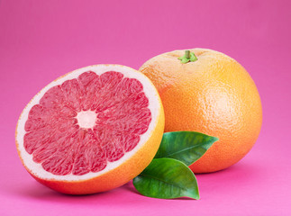 Grapefruit and grapefruit slice isolated on pink background.