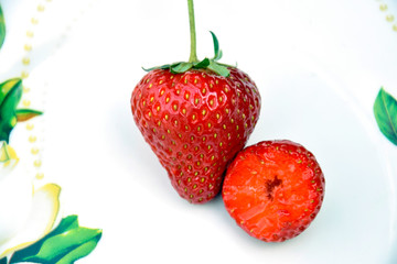 Two Ripe Red Strawberrys on a plate. Whole And Half. Summer harvest. Close-up. Selective focus. Copy space.
