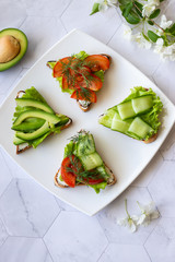 Vegetarian sandwiches with avocado, tomatoes and cucumbers on a light background