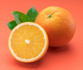 Orange fruit with orange slices and leaves isolated on orange background.