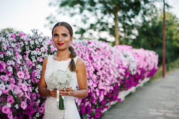 Beautiful bride shooting next to purple flowers and smelling them