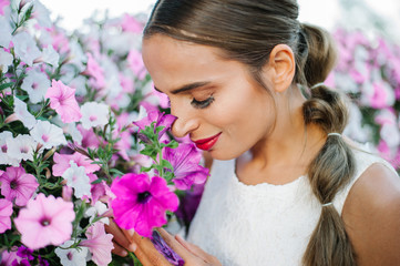 Obraz na płótnie Canvas Beautiful bride shooting next to purple flowers and smelling them