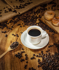 Coffee cup and roasted coffee beans. on wooden background with sunlight.