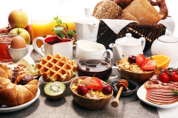 Huge healthy breakfast on table with coffee, orange juice, fruits, waffles and croissants. Good morning concept.