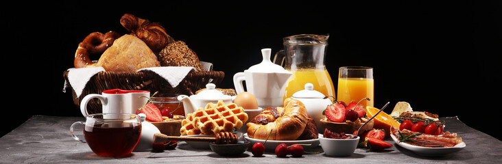Huge healthy breakfast on table with coffee, orange juice, fruits, waffles and croissants. Good...