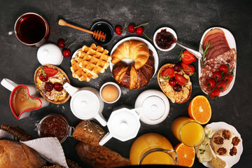 Huge healthy breakfast on table with coffee, orange juice, fruits, waffles and croissants. Good morning concept.