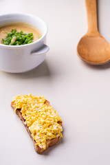 Cheese sandwich and soup puree with onion in the white plate with wooden spatula angle view
