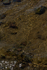 the sand and stones under water with the waves in the foreground .