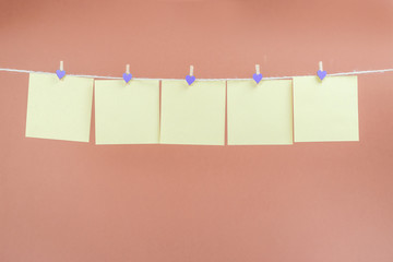 Yellow stickers on clothesline with clothespins isolated on brown background. Place for your text.