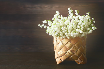 bouquet of lilies of the valley in a vase closeup. background with a bouquet of lilies of the valley on a wooden background.