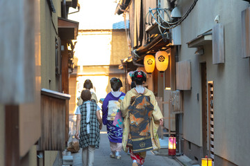 A group of geisha and maiko wearing traditional dress (kimono) walking on street in Kyoto, Japan....