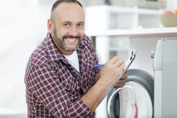 Naklejka na ściany i meble happy man fixing washing machine
