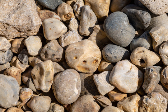 A full frame photograph of pebbles on a beach with one resembling a face
