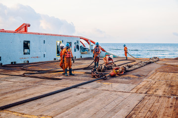 Anchor-handling Tug Supply AHTS vessel crew preparing vessel for static tow tanker lifting. Ocean...