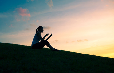 Woman silhouette outdoors reading on her phone