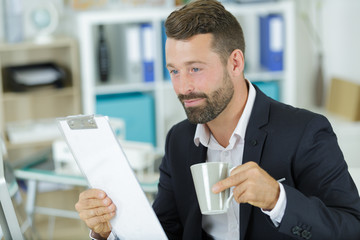man holding a coffee in his office
