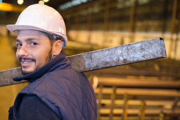construction worker carrying reinforcement rods at building site