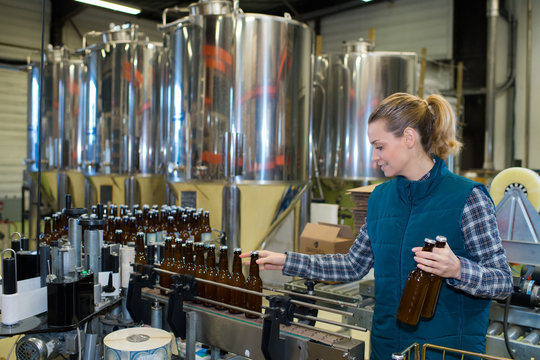 young female worker near tank on beer brewery factory