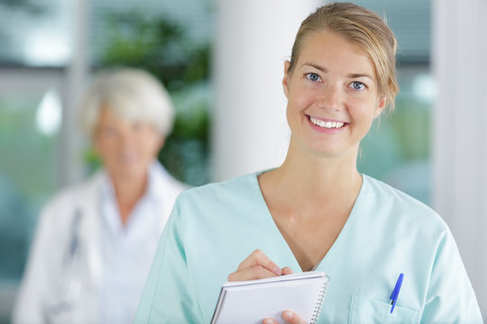 Woman Nurse In White Coat Records In A Notebook