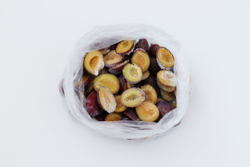 Frozen plums in a transparent package located on a white background