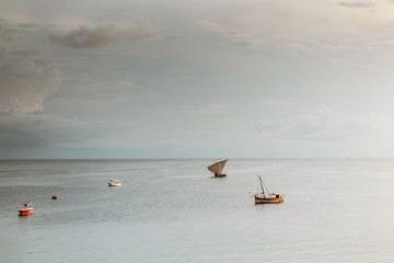 Naklejka premium old sailing boat in the ocean at sunset