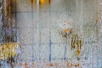 Water droplets on window glass. An iron grille for protection is visible behind the glass. Abstract image. 