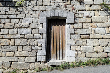 Fototapeta na wymiar Wooden door in the stone wall