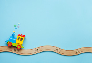 Kids toy train on toy wooden railway on blue background with copy space